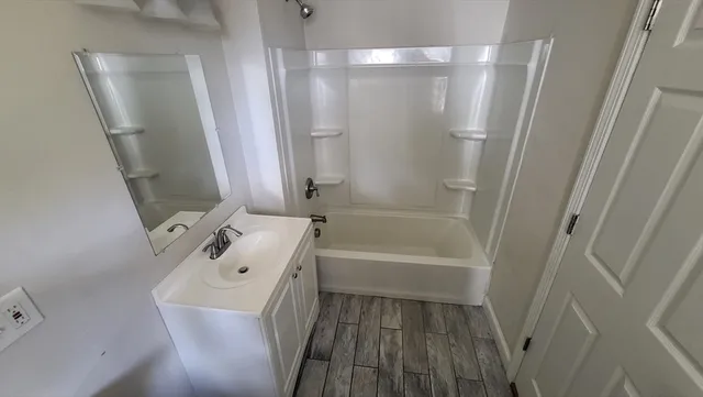 a bathroom with a tub sink vanity and mirror