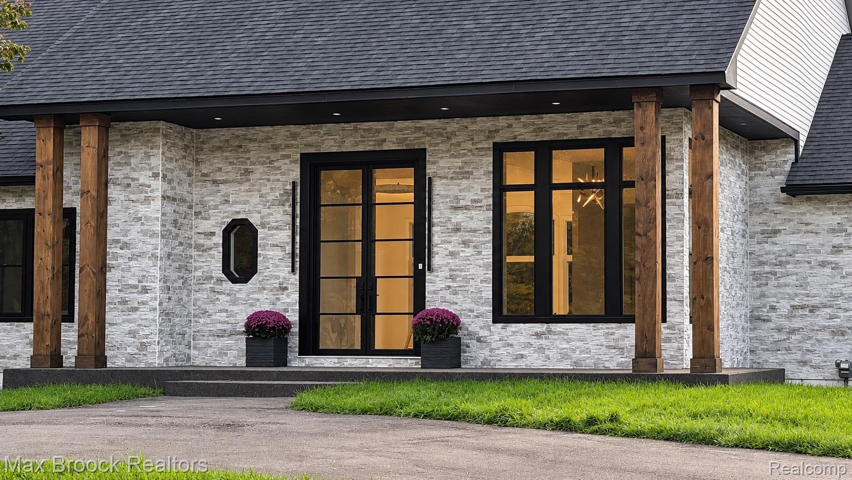 Stone-clad exterior featuring a charcoal shingle roof, black frame windows, and wood support columns