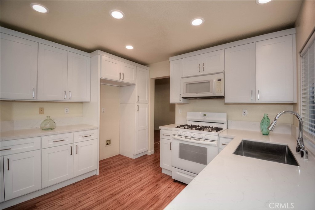 554 Pointe Vista Court Corona, CA 92881 - Photo 11 of 31 a kitchen with white cabinets and white appliances