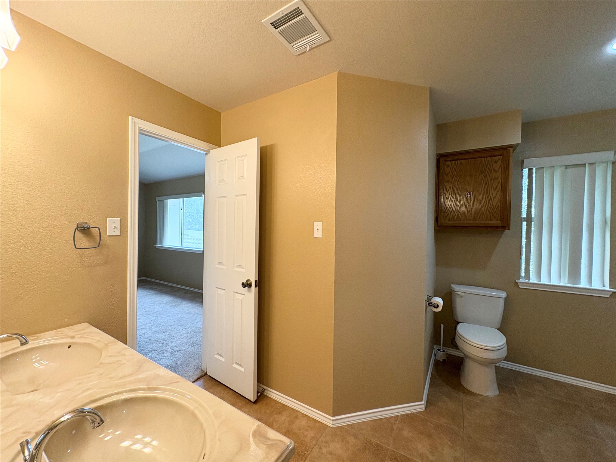 8103 Ephraim Road Austin, TX 78717 - Photo 26 of 35 Double vanities and tile flooring offer a pleasant, convenient bathing space with direct access to a carpeted bedroom.