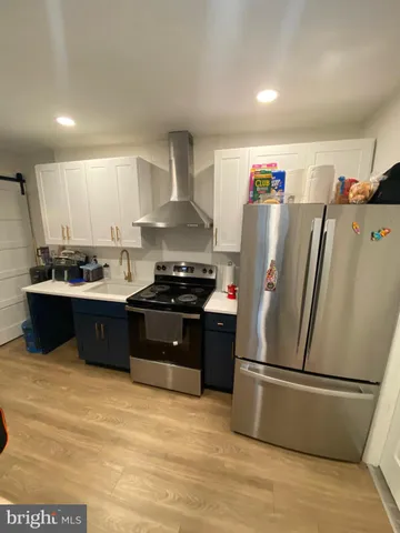 a kitchen with stainless steel appliances a refrigerator a sink a stove and white cabinets