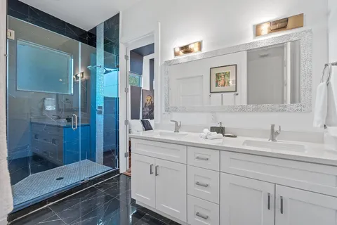 a en suite bathroom with a granite countertop sink mirror and shower