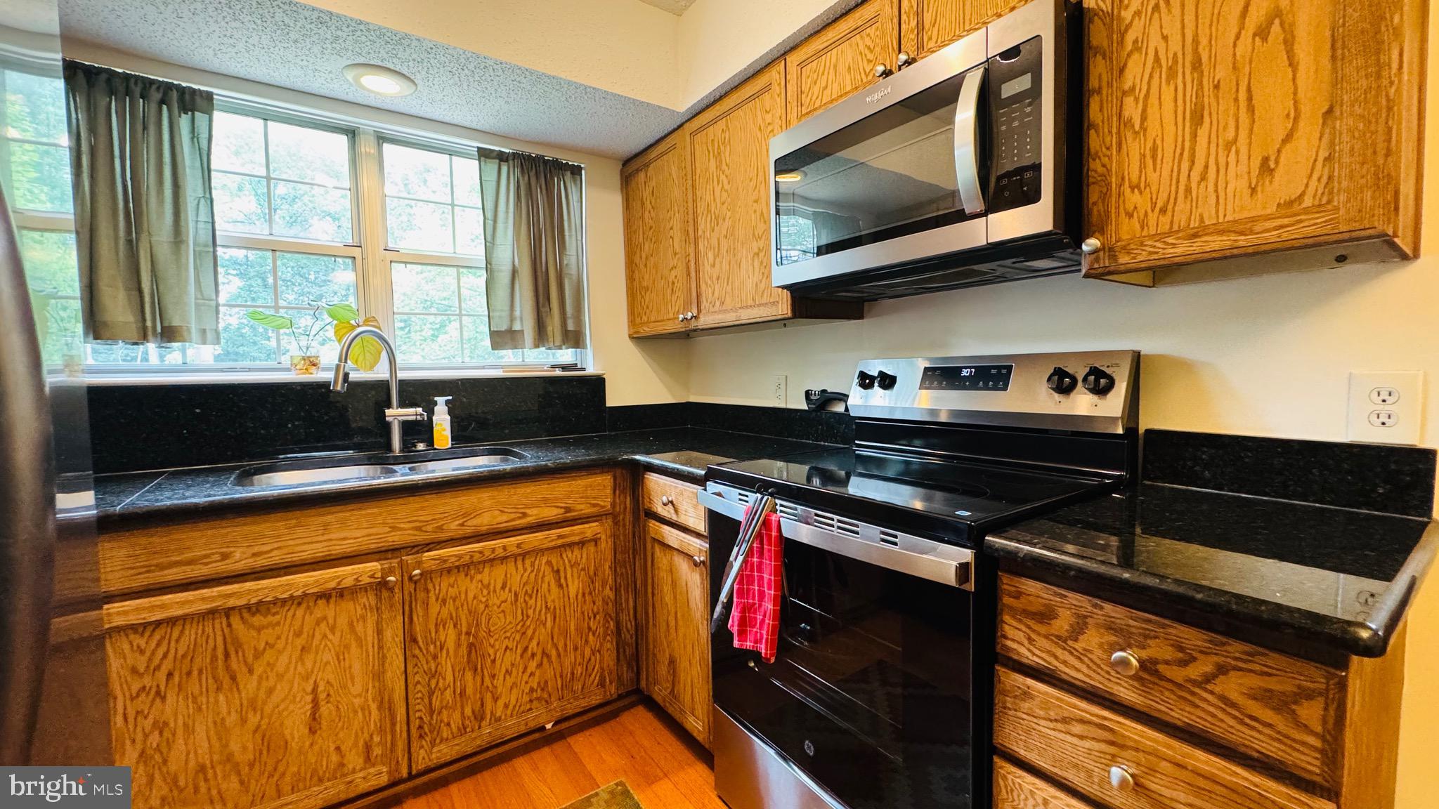 12012 Golf Ridge Court, Unit 374 Fairfax, VA 22033 - Photo 8 of 38 a kitchen with stainless steel appliances granite countertop a stove a sink and a microwave