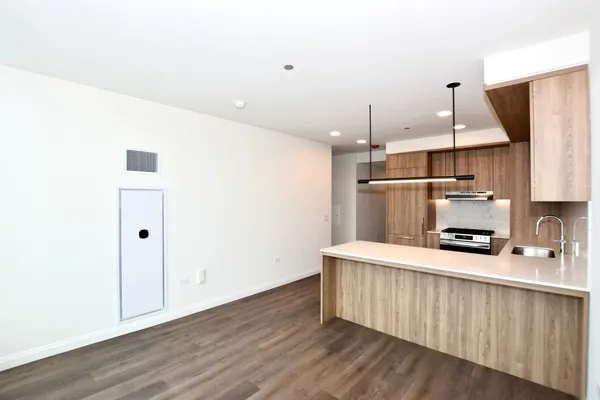 a kitchen with stainless steel appliances a wooden floor a sink a refrigerator and a stove