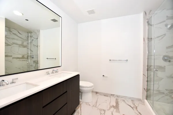 a bathroom with a double vanity sink toilet and shower