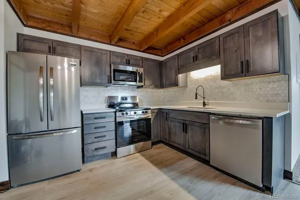 a kitchen with stainless steel appliances granite countertop a refrigerator a sink a stove and a microwave