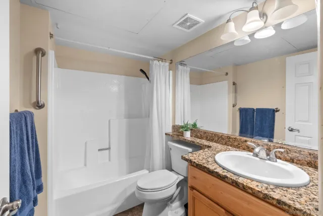 a bathroom with a granite countertop sink toilet a mirror a vanity and shower
