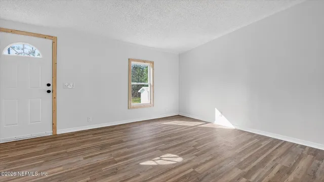 an empty room with wooden floor fireplace and windows