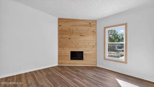 a view of empty room with wooden floor and fireplace