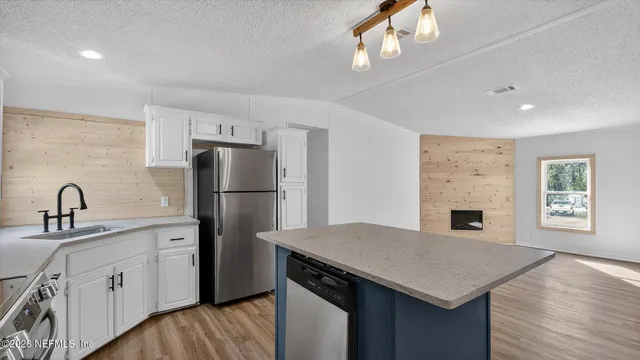 a kitchen with stainless steel appliances granite countertop a refrigerator a sink dishwasher a stove and a refrigerator with wooden floor