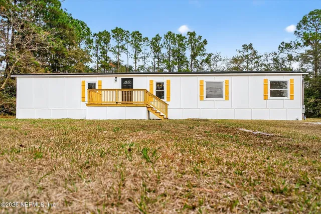 a front view of house with yard and trees in the background