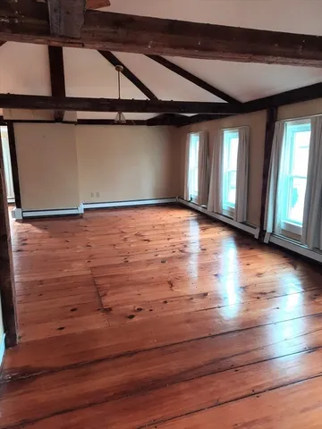 a view of an empty room with window and wooden floor
