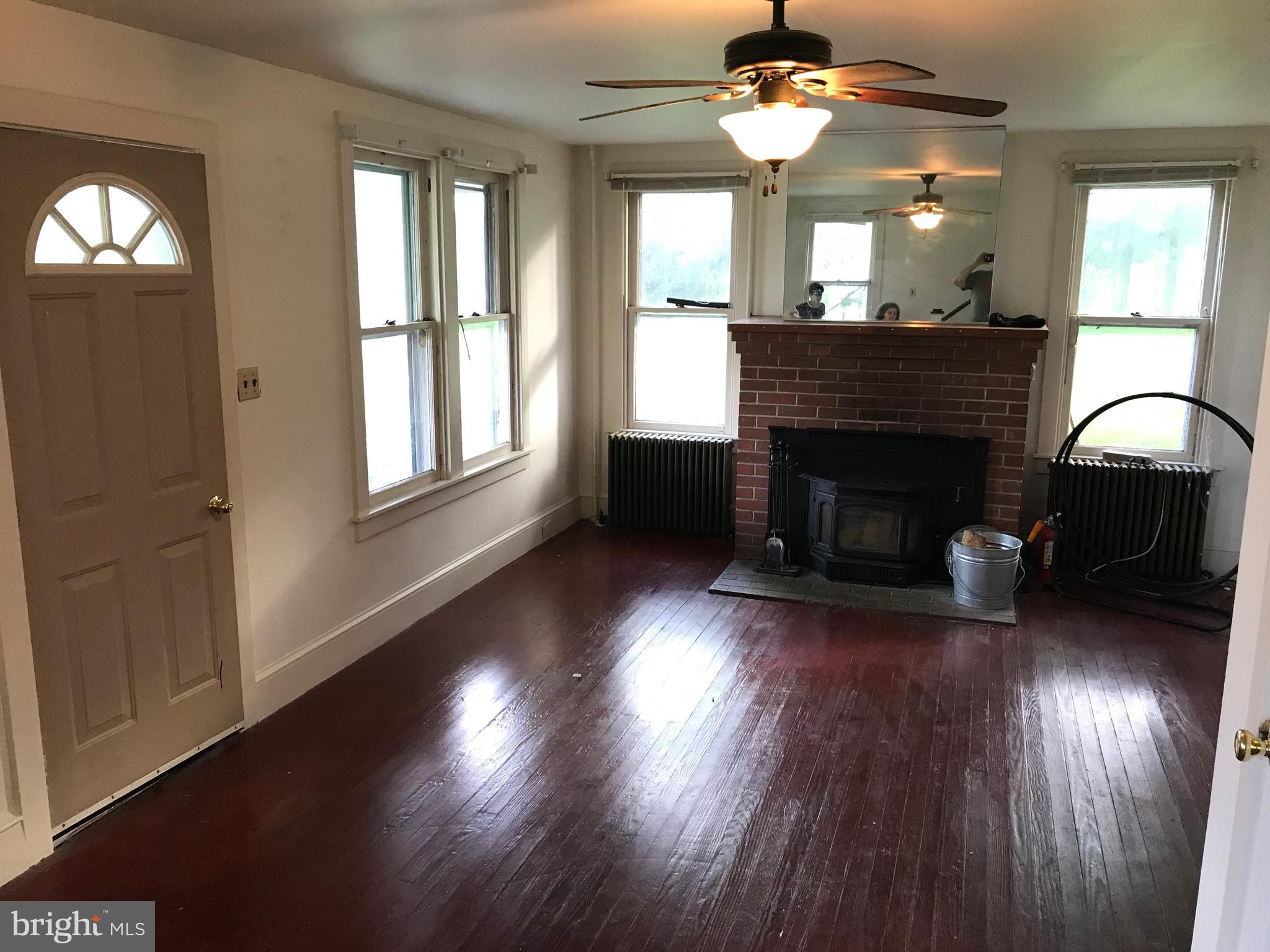 2033 Hopewell Road Oxford, PA 19363 - Photo 8 of 19 an empty room with wooden floor fireplace cabinet and windows