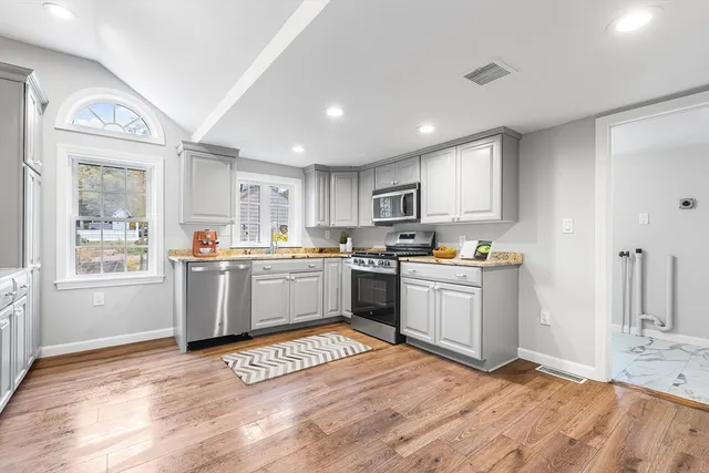 a kitchen with granite countertop a stove top oven a sink dishwasher and a refrigerator with wooden floor