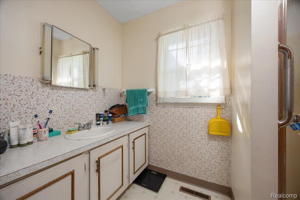 59380 10 Mile Road South Lyon, MI 48178 - Photo 16 of 53 Vanity with integrated sink, wall-mounted mirror cabinet, tiled backsplash, and window