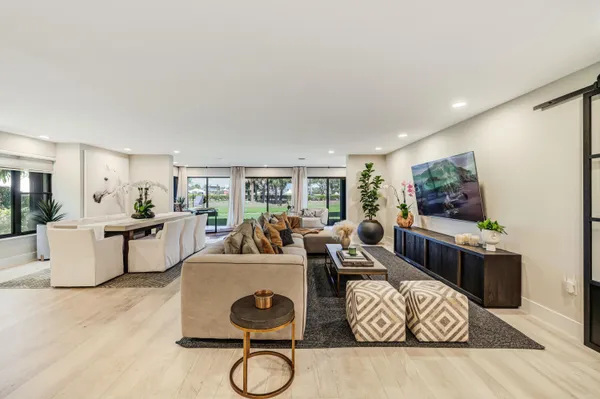 a living room with furniture a rug kitchen view and a large window