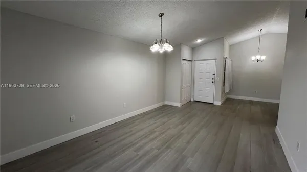 an empty room with wooden floor and hallway