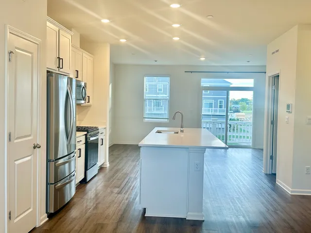 a kitchen with stainless steel appliances a stove top oven a refrigerator a sink and dishwasher with wooden floor