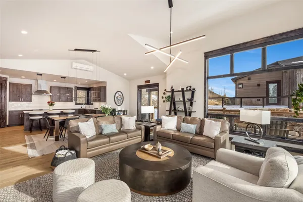 a living room with furniture kitchen view and a chandelier