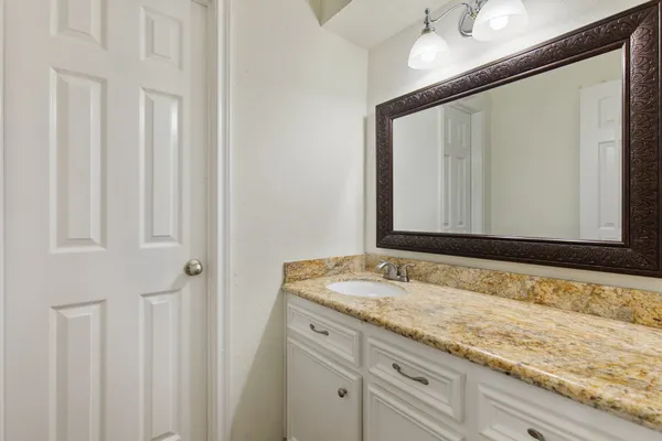 a bathroom with a granite countertop sink and a mirror