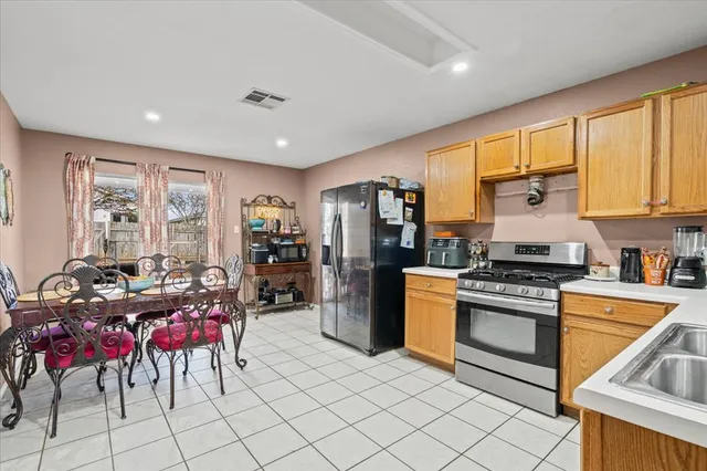 a kitchen with stainless steel appliances granite countertop a stove a refrigerator a oven with white cabinets and wooden floor