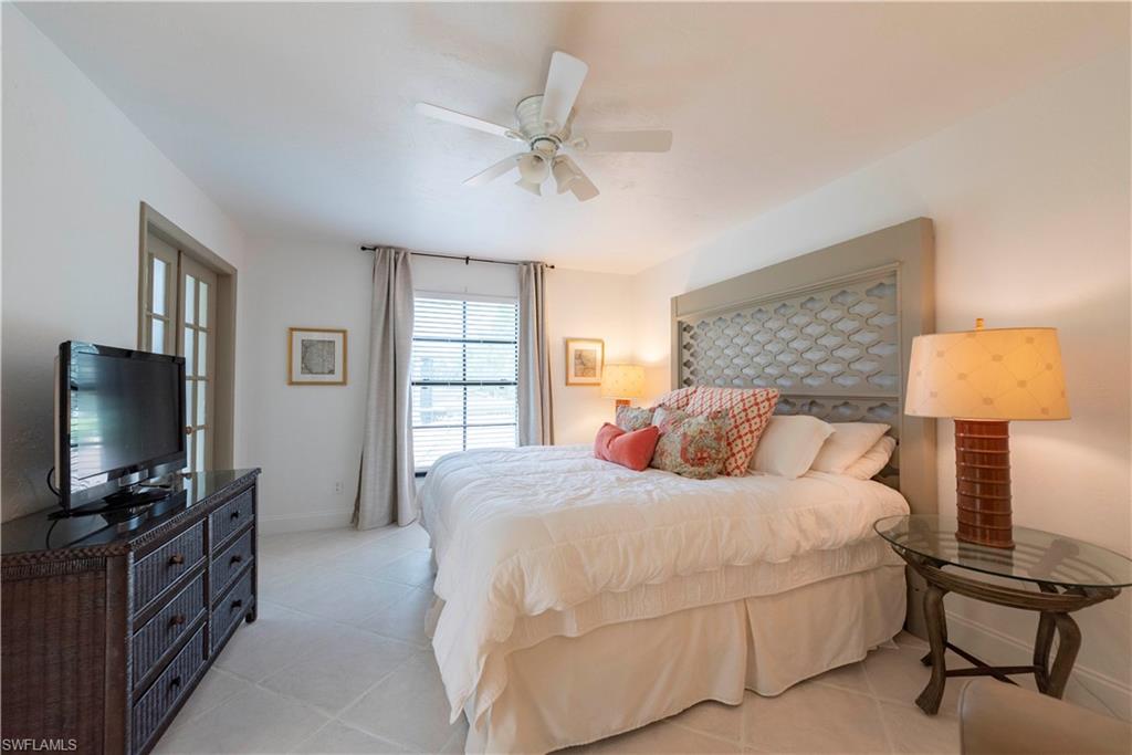 3107 Riviera Drive, Unit A202 Naples, FL 34103 - Photo 13 of 25 a bedroom with a bed and a flat screen tv