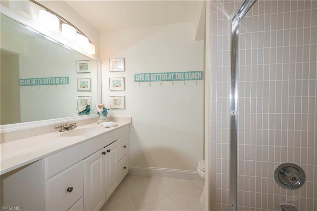 3107 Riviera Drive, Unit A202 Naples, FL 34103 - Photo 19 of 25 a bathroom with a double vanity sink a toilet and a mirror