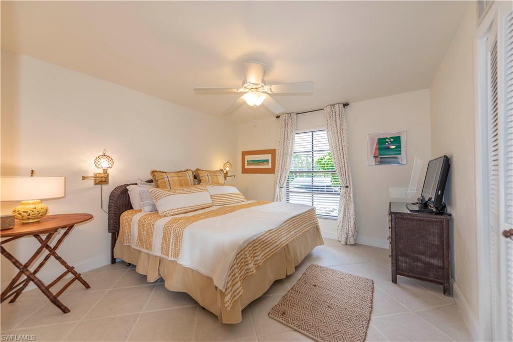3107 Riviera Drive, Unit A202 Naples, FL 34103 - Photo 21 of 25 a bedroom with a bed and a chandelier with a dresser