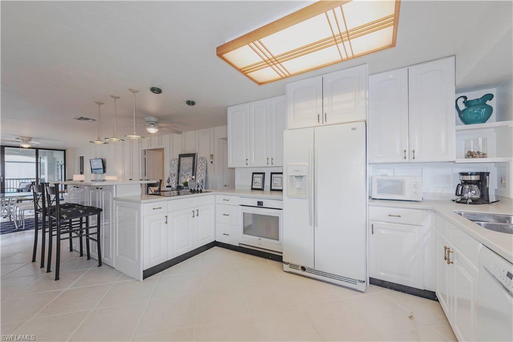 3107 Riviera Drive, Unit A202 Naples, FL 34103 - Photo 3 of 25 a kitchen with white cabinets and white appliances
