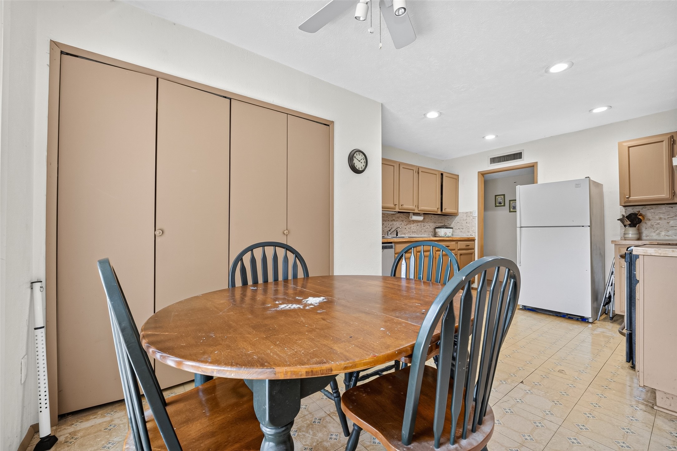 22926 Millgate Drive Spring, TX 77373 - Photo 16 of 34 Cozy kitchen with a round wooden dining table and four chairs. Features ample storage with beige cabinets, a ceiling fan, and a white refrigerator.