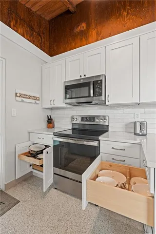 a kitchen with stainless steel appliances granite countertop a sink a stove and a microwave oven with white cabinets