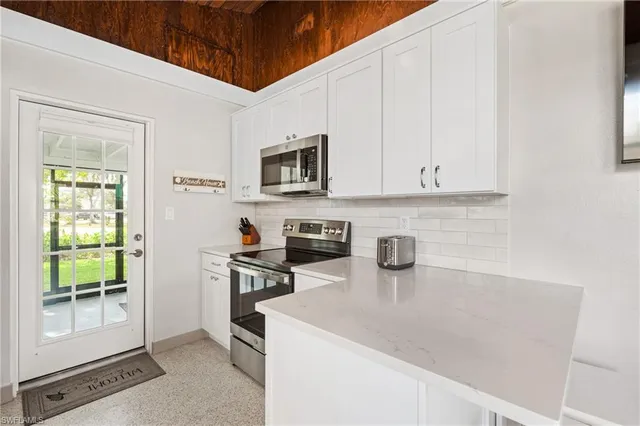 a kitchen with stainless steel appliances a stove a sink and white cabinets