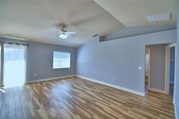 a view of an empty room with a window and wooden floor