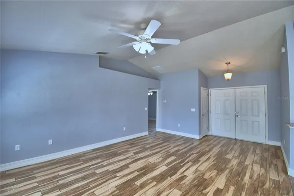 a view of an empty room with window and chandelier fan