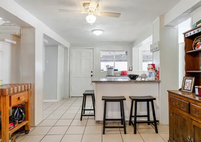 a kitchen with stainless steel appliances kitchen island granite countertop a table chairs and a refrigerator