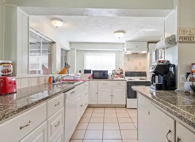 a kitchen with granite countertop sink stainless steel appliances and window
