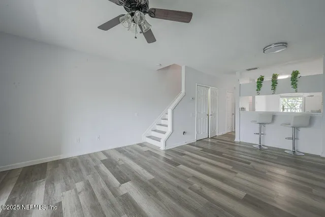 a view of empty room with wooden floor and fan