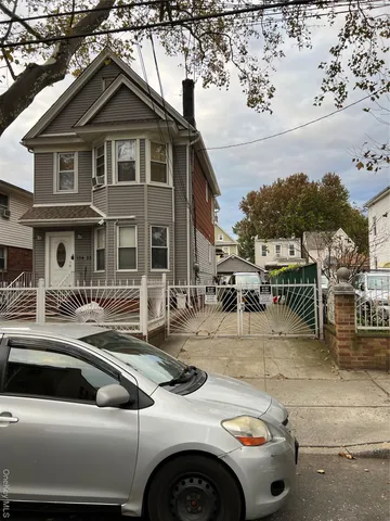 a view of a white house with lawn chairs under an umbrella
