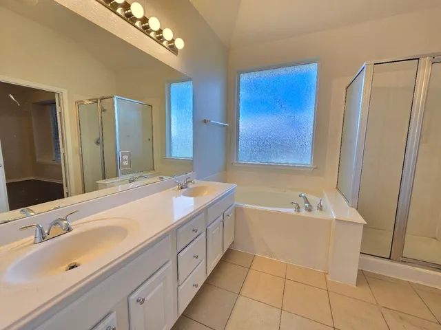 a spacious bathroom with a tub sink and mirror