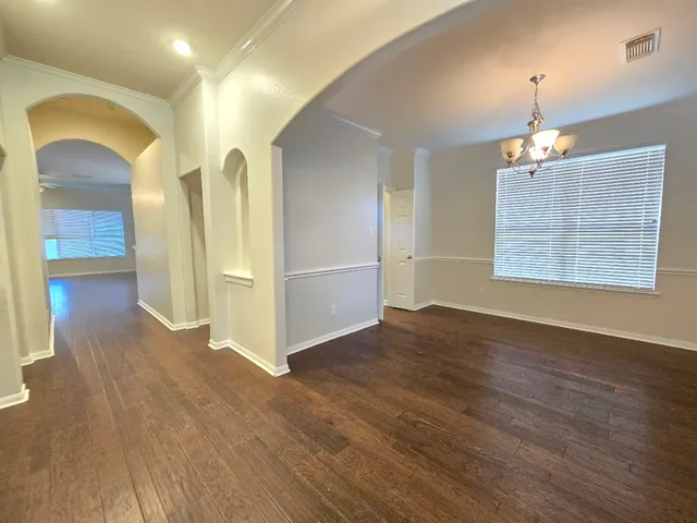an empty room with wooden floor closet and windows