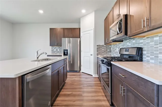 a kitchen with stainless steel appliances granite countertop a sink a stove and a refrigerator