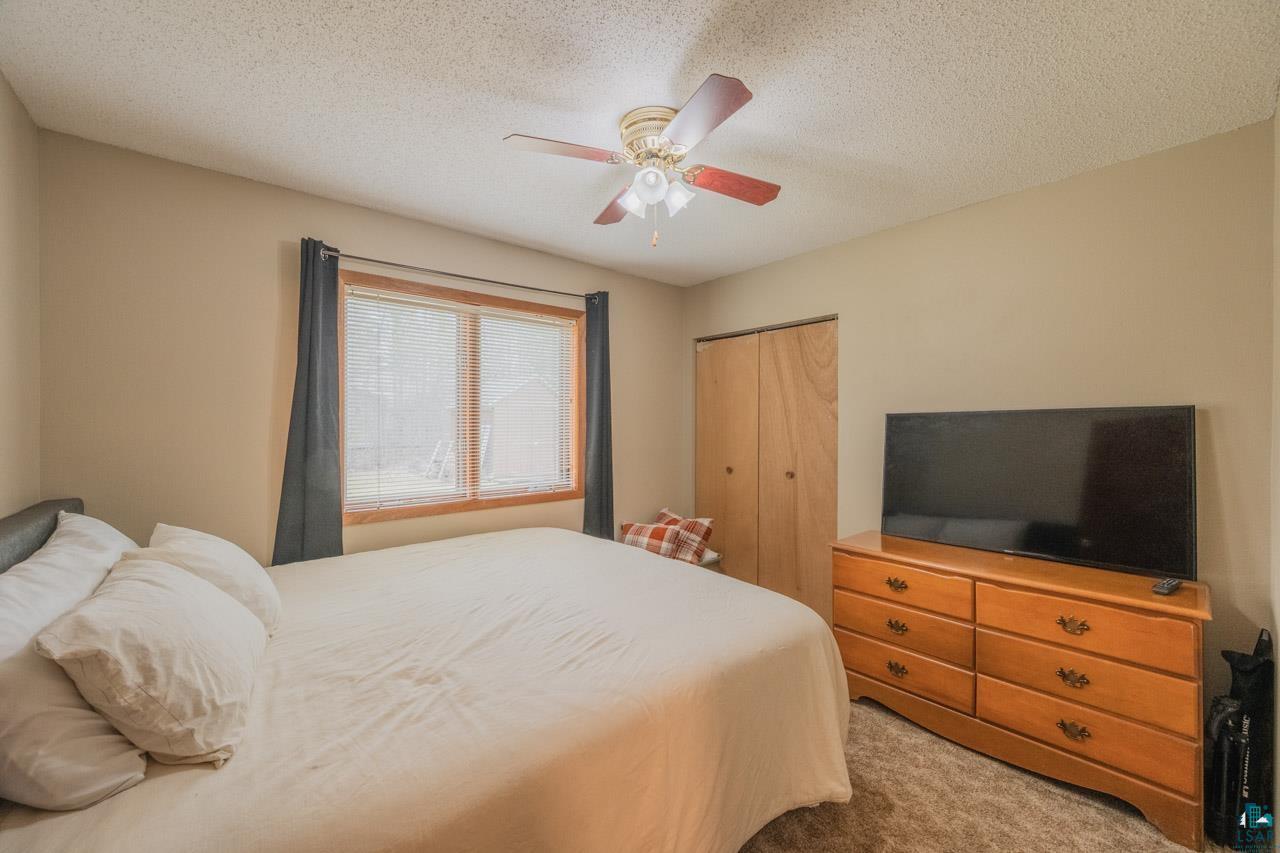 228 3rd Street Southeast Cook, MN 55723 - Photo 13 of 30 Bedroom featuring neutral wall paint, a window with wood trim and blinds, a ceiling fan with integrated lighting, and a bi-fold closet with wood-finish doors