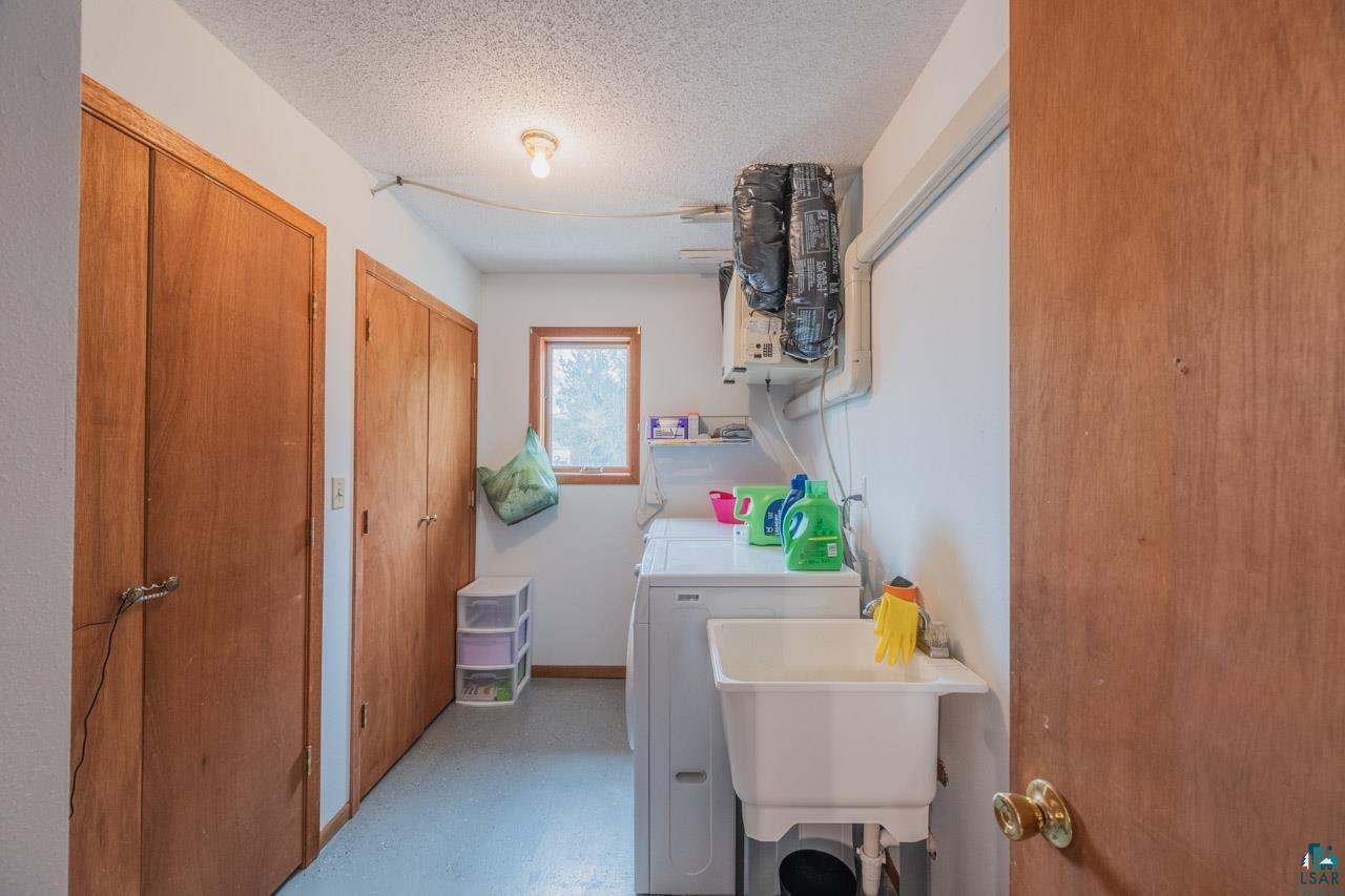 228 3rd Street Southeast Cook, MN 55723 - Photo 17 of 30 Dedicated utility room featuring a utility sink, washer, dryer, built-in shelving, and two wood-paneled storage closets