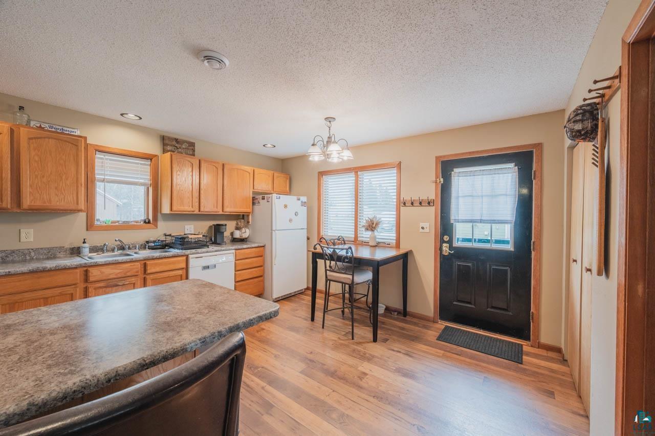 228 3rd Street Southeast Cook, MN 55723 - Photo 6 of 30 Kitchen featuring wood-finish flooring, a central island with a stone-look countertop, wood cabinetry, a double basin sink, and a black exterior door with a window