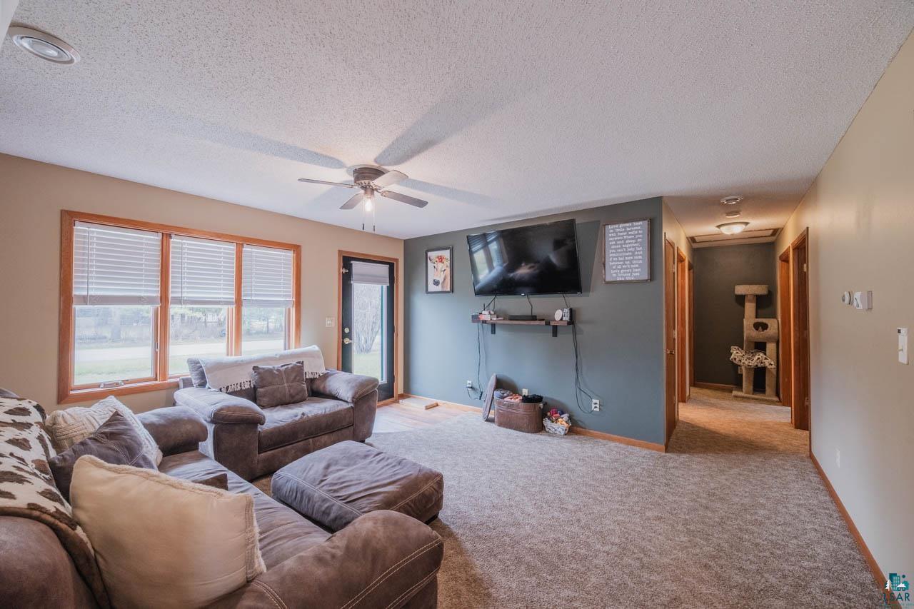 228 3rd Street Southeast Cook, MN 55723 - Photo 8 of 30 Spacious living area featuring carpet flooring, natural light from multiple windows, and a ceiling fan