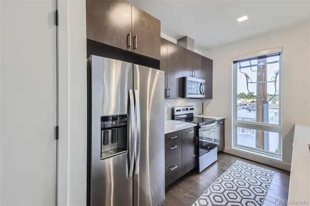 a kitchen with stainless steel appliances granite countertop a refrigerator and a stove top oven
