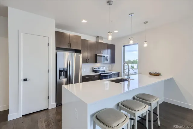 a kitchen with a dining table chairs refrigerator and microwave