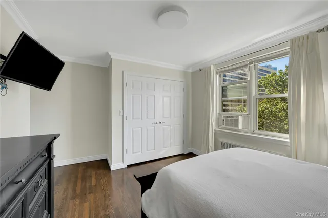 a bedroom with a bed tv and a window