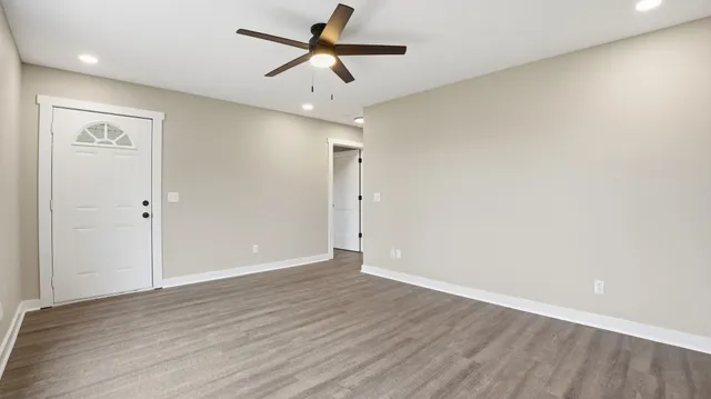 an empty room with wooden floor and ceiling fan