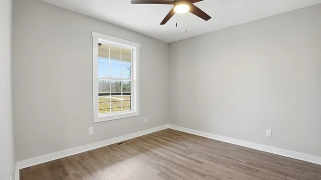 an empty room with wooden floor and a window